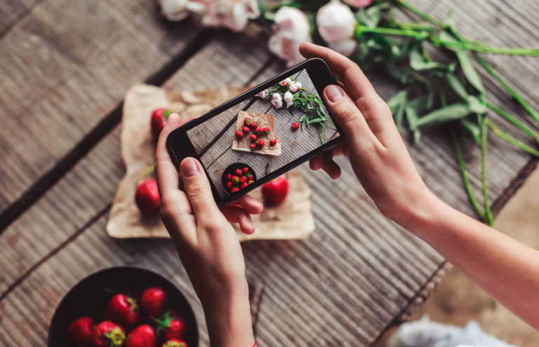 manos con movil fotografiando comida