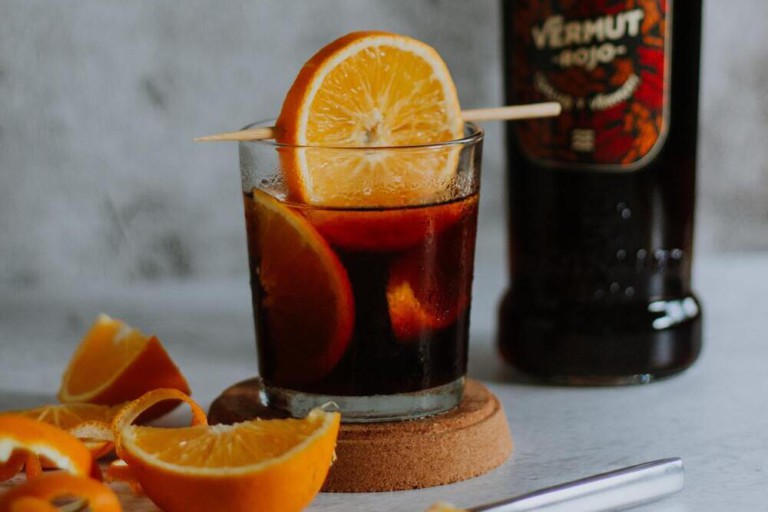Vaso de vermut rojo con botella de fondo