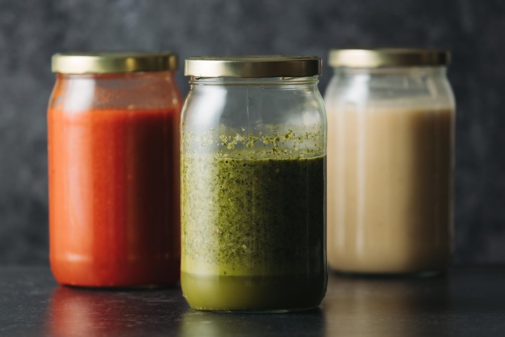 Tres frascos con salsas encurtidas, vinagres y encurtidos