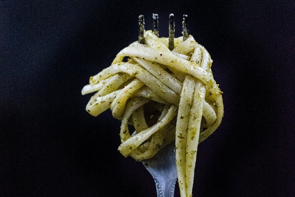 Tenedor con pasta al pesto, cocina mediterránea con ingredientes de temporada