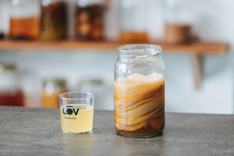 Frasco con kombucha y vaso con bebida, aromatizar la kombucha