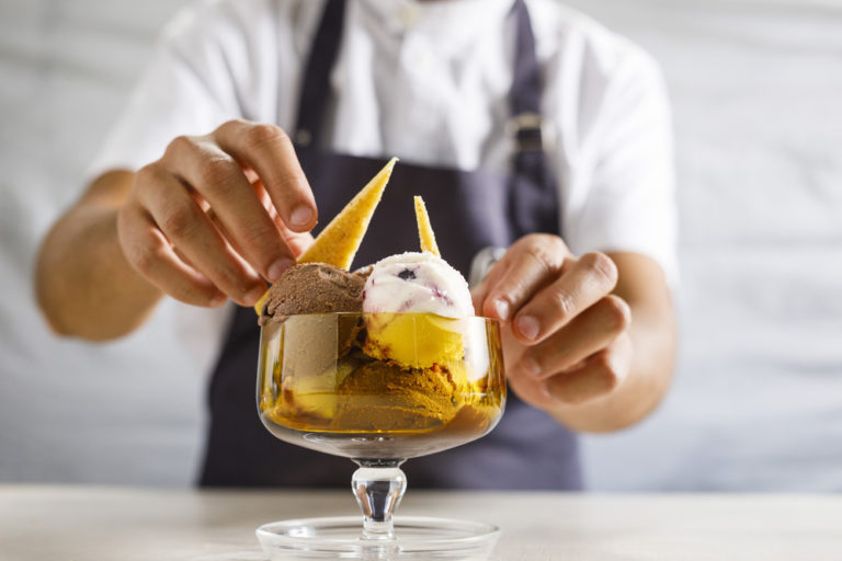 Manos arreglando una copa de helado, helados veganos