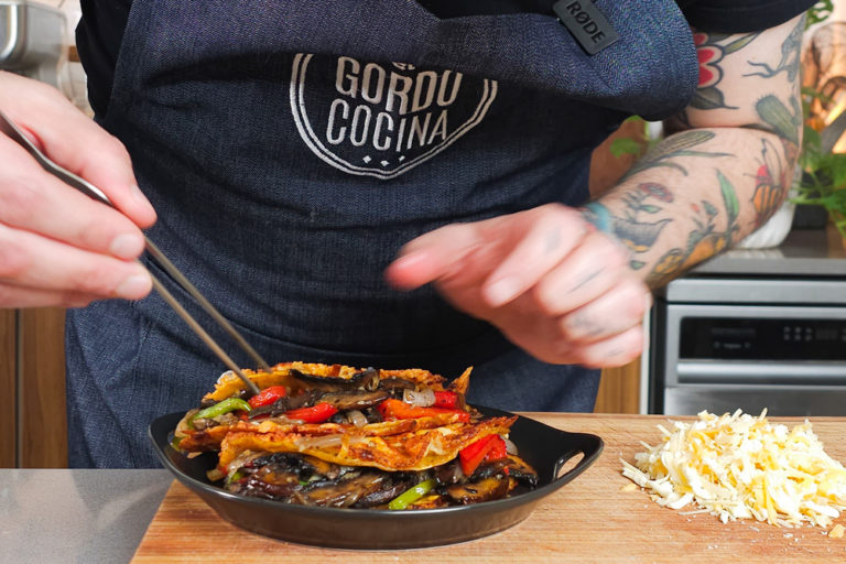 Manos con pinza sobre costra mexicana vegetariana.