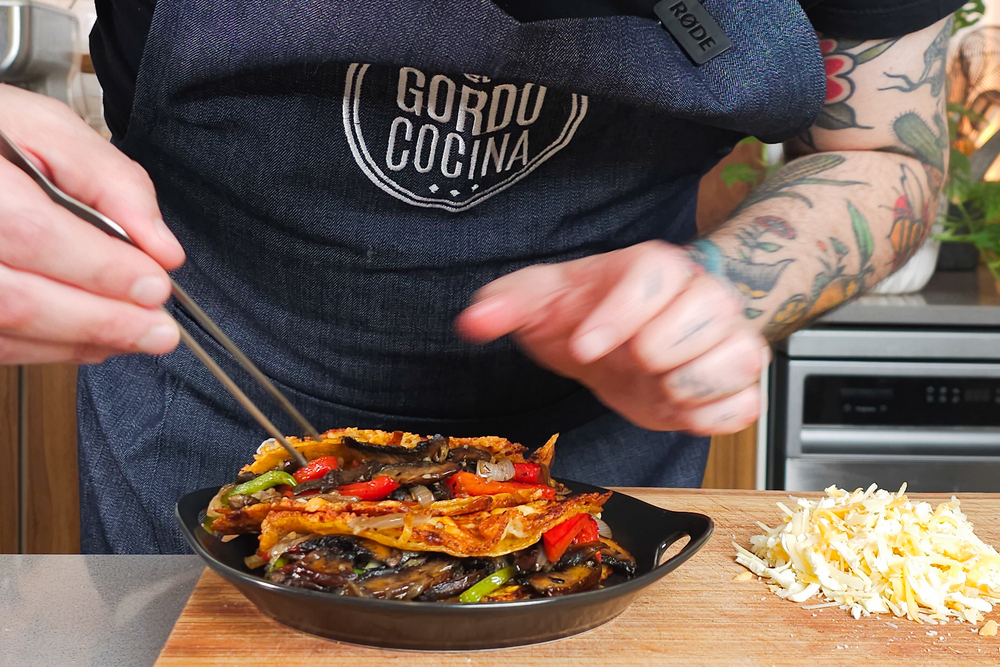 Manos con pinza sobre costra mexicana vegetariana.