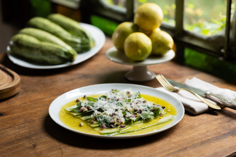 Bodegón con receta de carpaccio, limones y calabacines de fondo