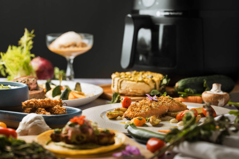 Distintos platos y airfryer de fondo, ventajas de utilizar una airfryer