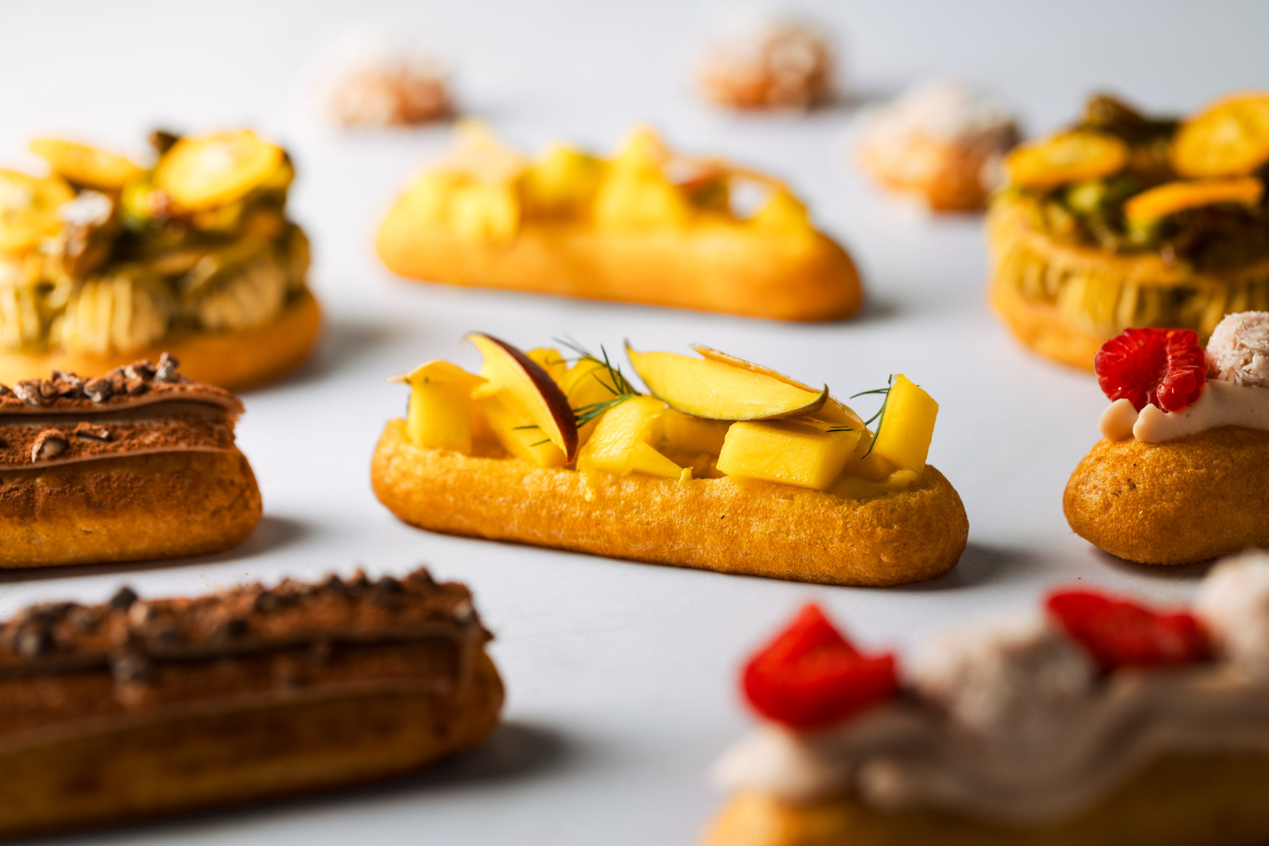 Éclairs con masa choux rellenos de mango, frambuesa y coco