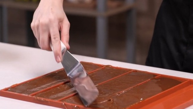 Verter y extender el toffee en moldes rectangulares de silicona