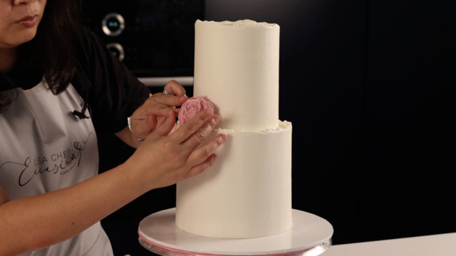 Colocar rosas de crema de mantequilla en un pastel de celebración.